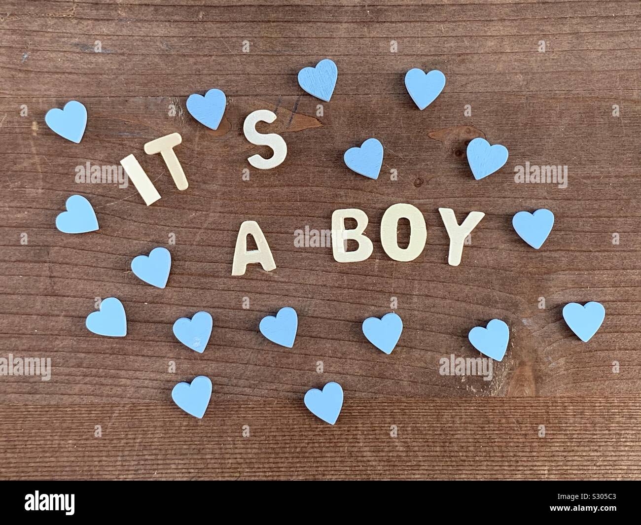It’s a boy, congratulations message for a new born with wooden letters and blue hearts Stock Photo