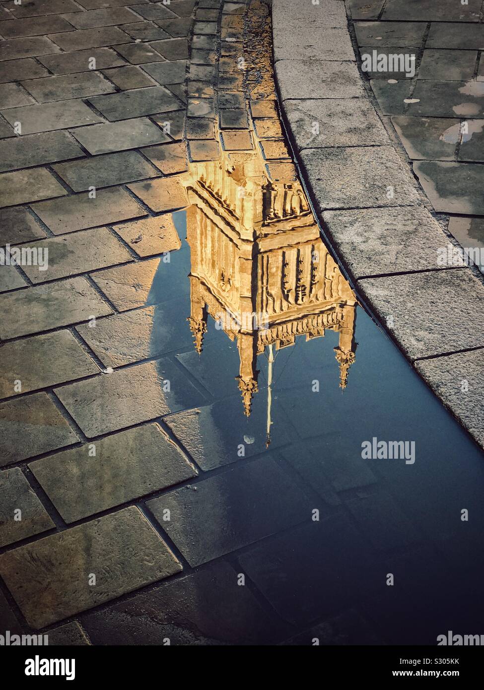 Reflection of a large Anglican Church Bell Tower in a puddle - somewhere in Southern England. Photo Credit - © COLIN HOSKINS. - Smartphone Captured Stock Image