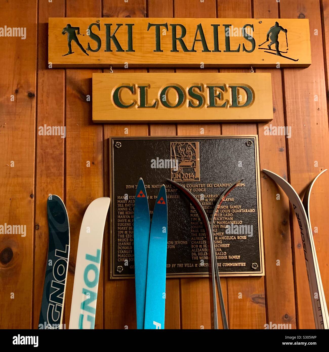 Skis against a wall under signs reading “Ski Trails Closed.” Mid November in the Outdoor Center, Trapp Family Lodge, Stowe, Vermont, United States - Smartphone Captured Stock Image