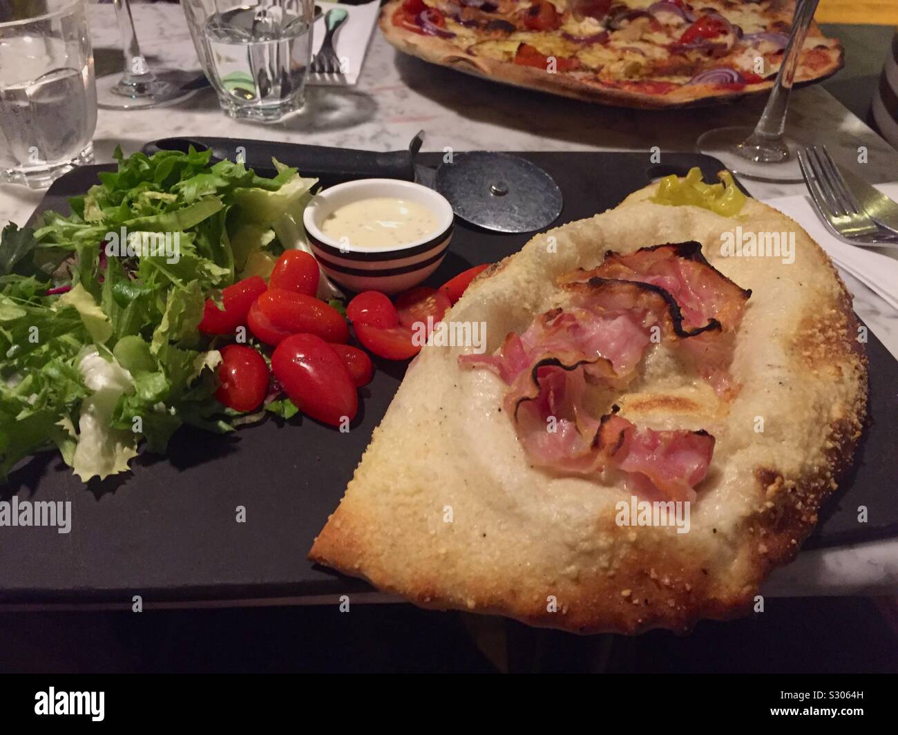 Closed pizza called “calzone” with salad.Soft and spicy sausage,red chilli,peppers,mozzarella,tomato,rocket,pesto and Italian cheese. - Smartphone Captured Stock Image
