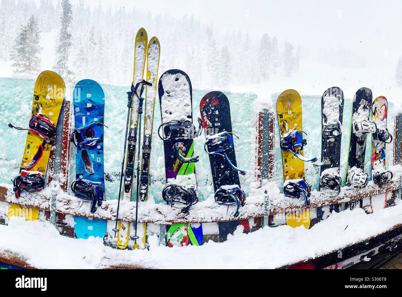 Snowboards and one pair of skis lined up against glass wall during blizzard at Mammoth Mountain CALIFORNIA Stock Photo