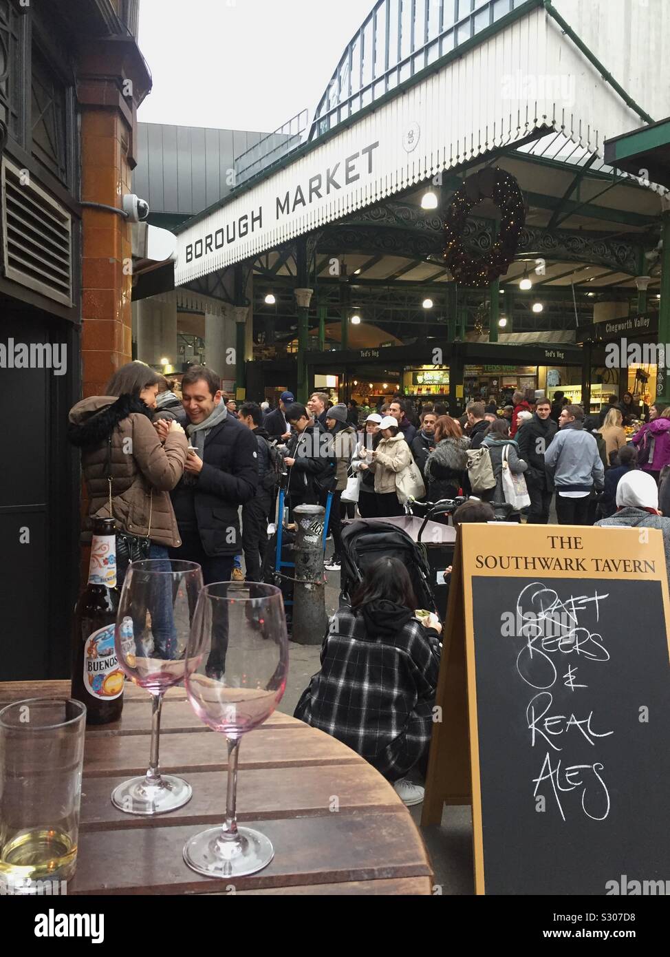 Borough market in London this weekend. People have drinks in the nearby pubs before they try gourmet cheese and meant in the food market. - Smartphone Captured Stock Image