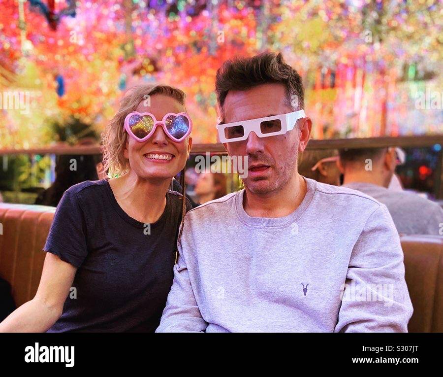 Woman smiling while man makes a silly face. Both wear glasses with lots ...