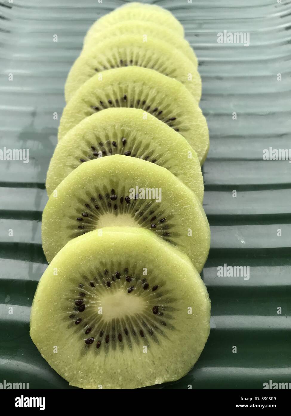 Kiwi fruit cut and arranged inline in melamine banana leaf plate Stock