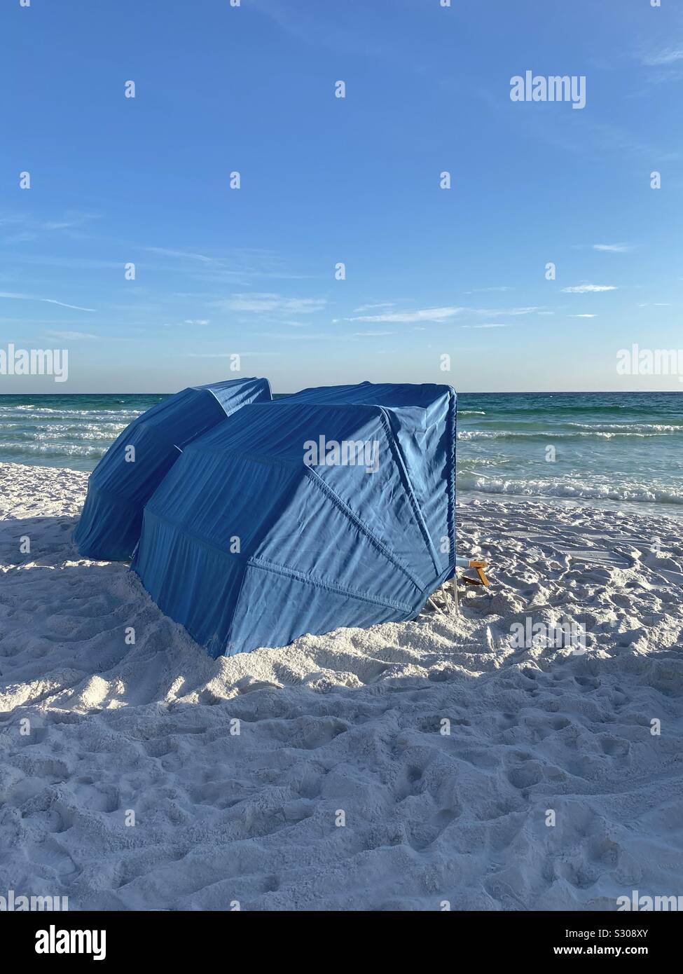 Beach tents on white sand beach with view of ocean water - Smartphone Captured Stock Image