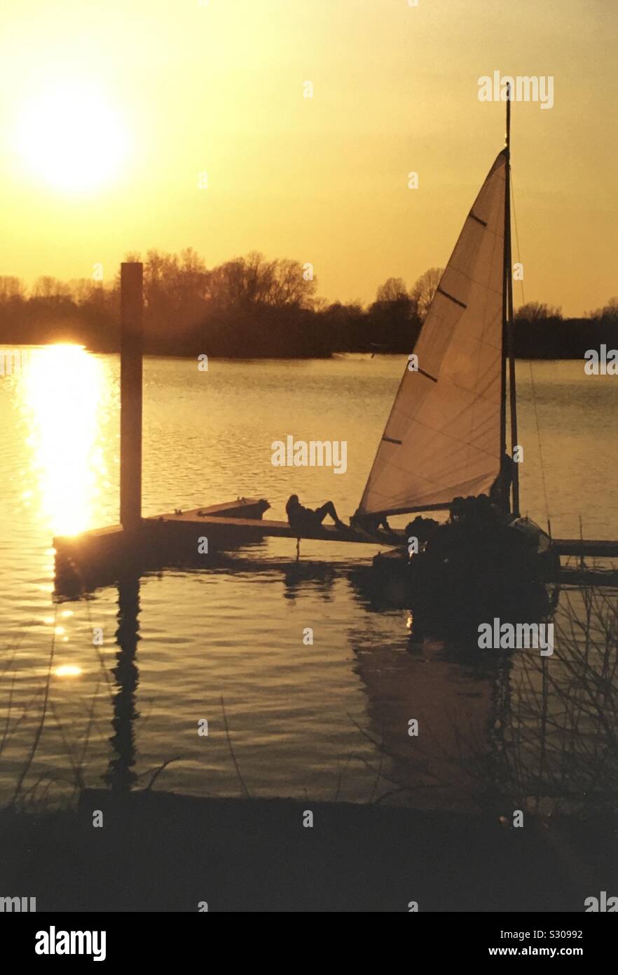 Romantischer Sonnenuntergang am See mit Segelboot Stock Photo