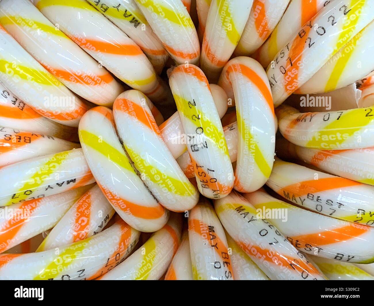 Full frame of many white Christmas candy canes with yellow and orange stripes - Smartphone Captured Stock Image