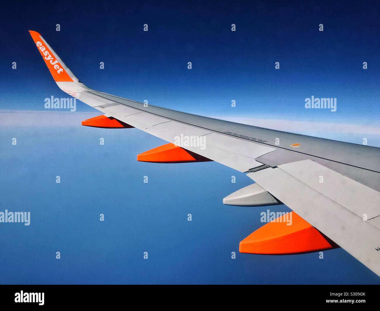 The wing of an EasyJet aircraft flying in bright sunshine, somewhere over Europe. Going to or coming back from a holiday? Business Trip? Aviation is fantastic! Photo Credit - © COLIN HOSKINS. - Smartphone Captured Stock Image