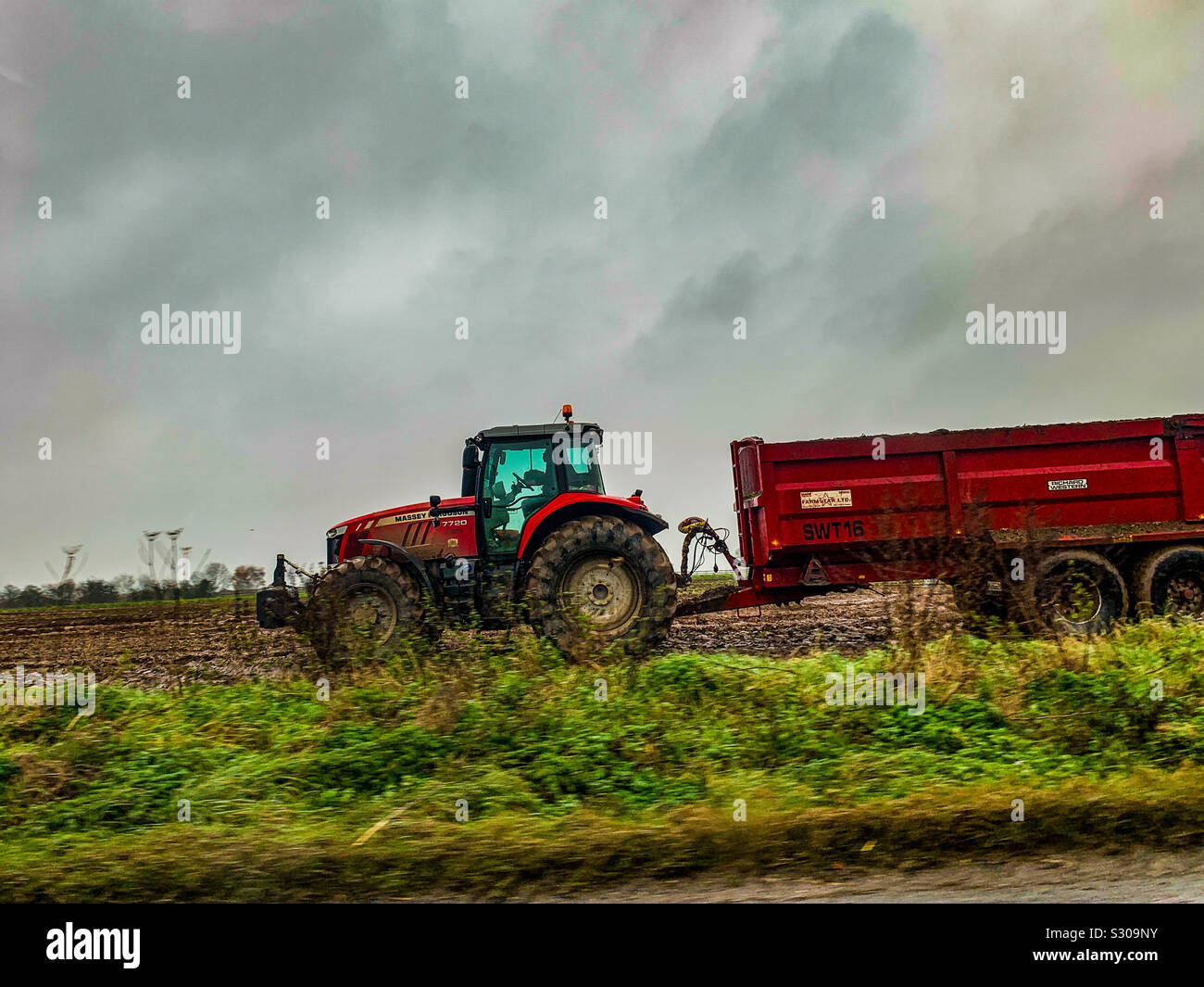 Red Massey Ferguson tractor in a muddy field - Smartphone Captured Stock Image