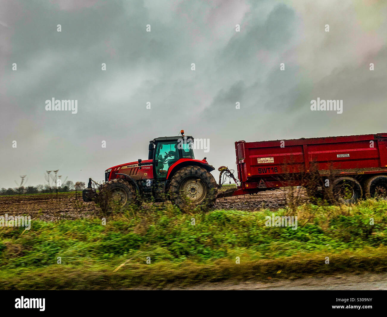 Red Massey Ferguson tractor in a muddy field Stock Photo