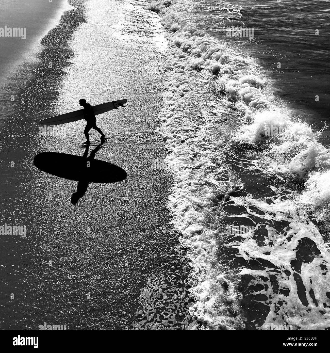 Male surfer walks up the beach after surfing. Manhattan Beach, California, USA. - Smartphone Captured Stock Image