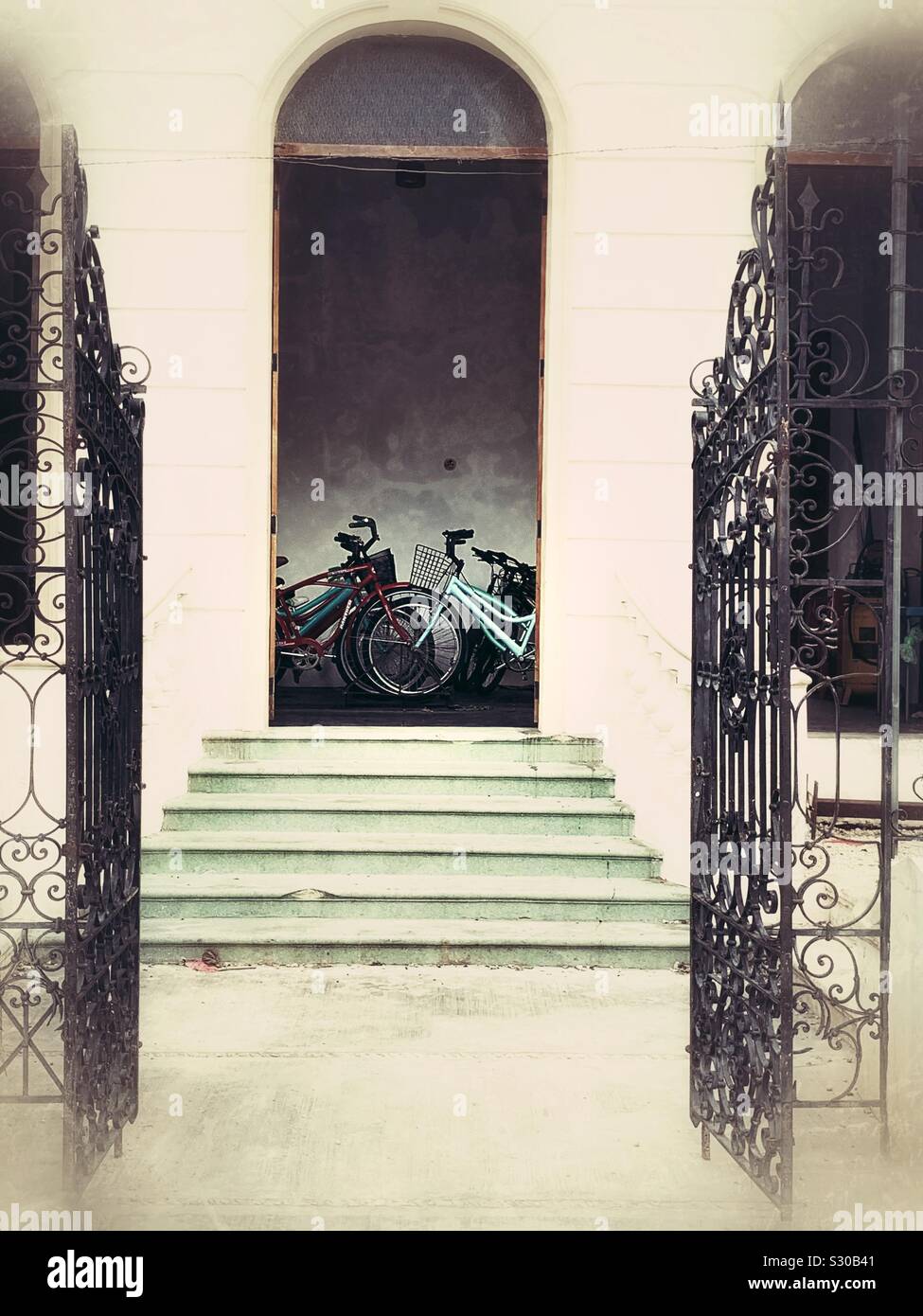 An open arched doorway provides a view into a bike shop in one of the restored mansions on Paseo de Montejo in Mérida, México. Stock Photo