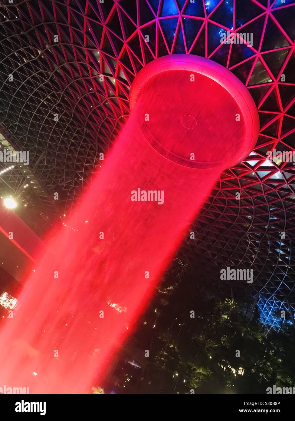 Red coloured - HSBC rain Vortex in Singapore Jewel Changi Airport- water gushing from 7 storey height-decorative light Stock Photo