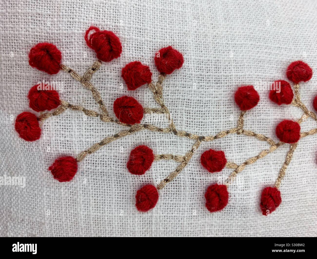 Beautiful embroidery of a golden brown tree branch with red blossoms - Smartphone Captured Stock Image