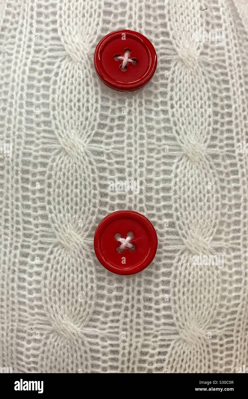 Closeup of a comfy cozy white sweater with two red buttons Stock Photo