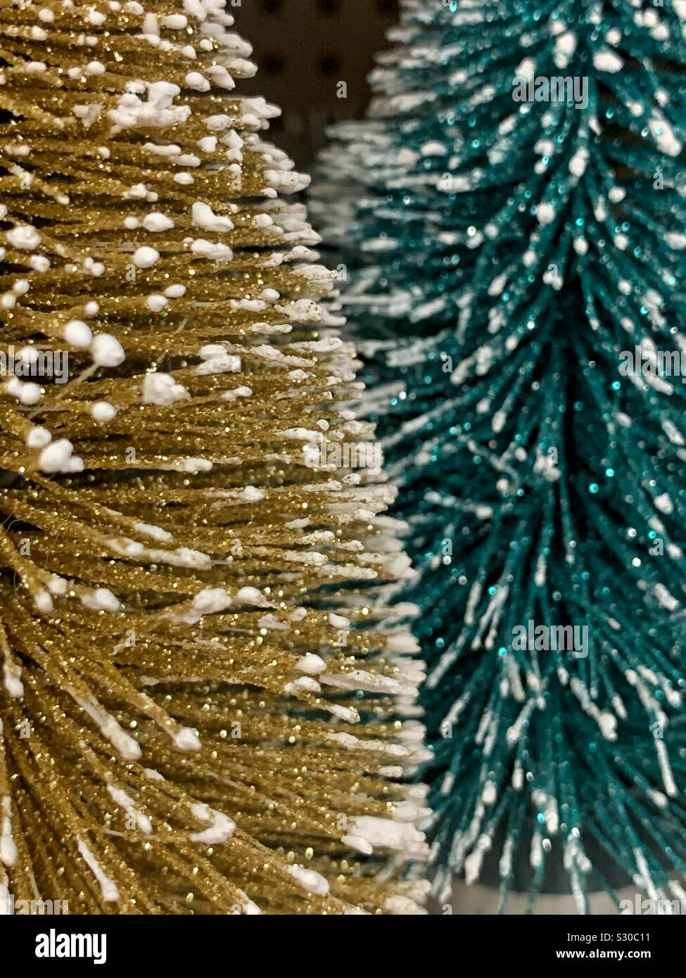 Closeup of two decorative green and gold Christmas pine tree with dabbles of snow - Smartphone Captured Stock Image