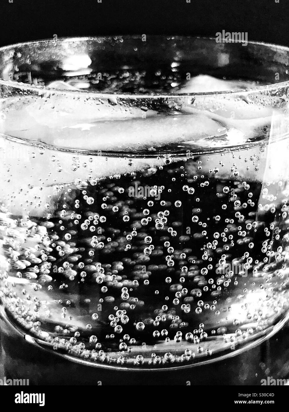 Close up of sparkling water and ice cubes in a glass tumbler Stock