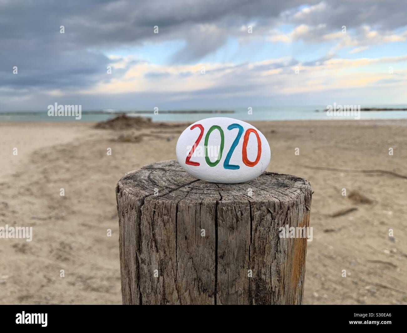 2020 year carved and colored on a stonewith empty beach background - Smartphone Captured Stock Image