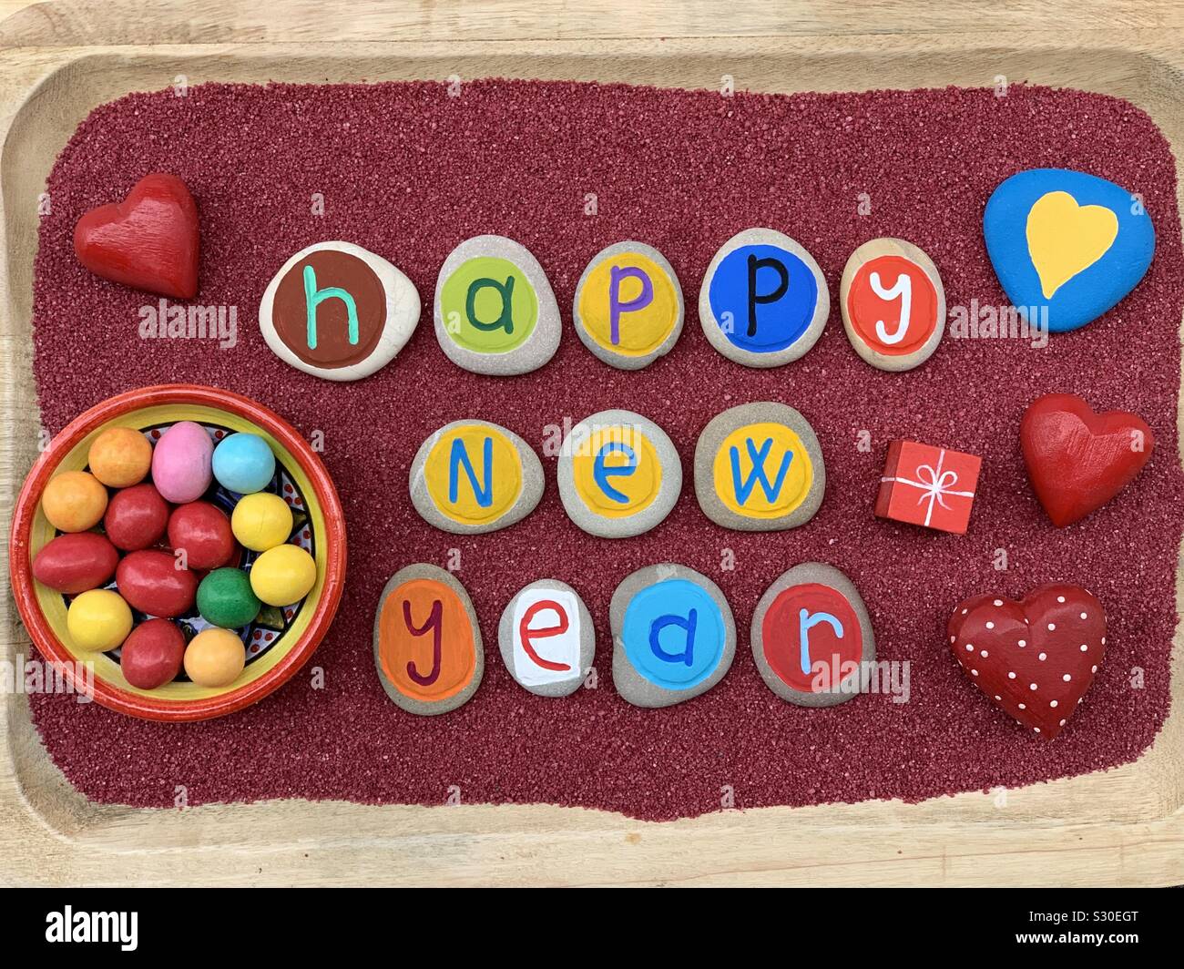 Happy New Year wmessage with creative stone colored and carved letters over red sand - Smartphone Captured Stock Image