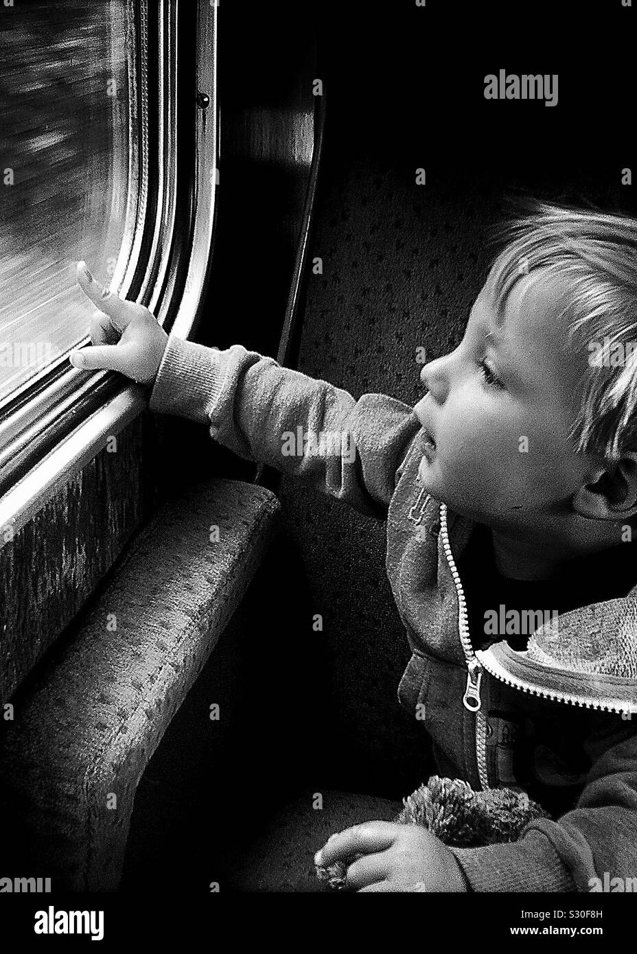 Young pre school boy looking out of a train window in monochrome Stock Photo