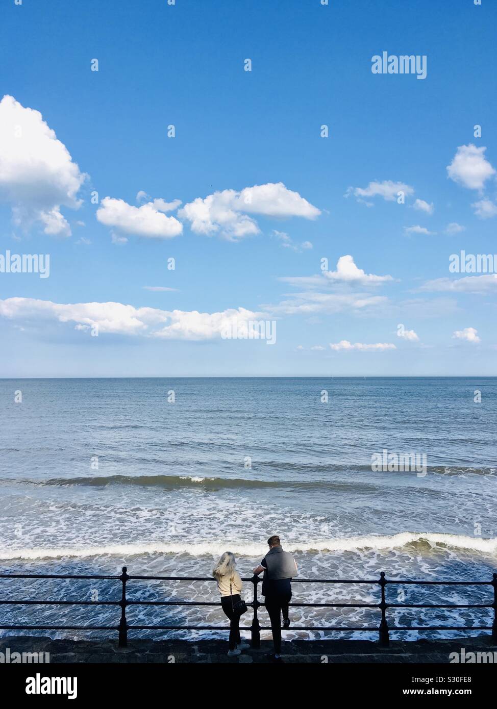 Couple looking over railings at Scarborough, Yorkshire - Smartphone Captured Stock Image