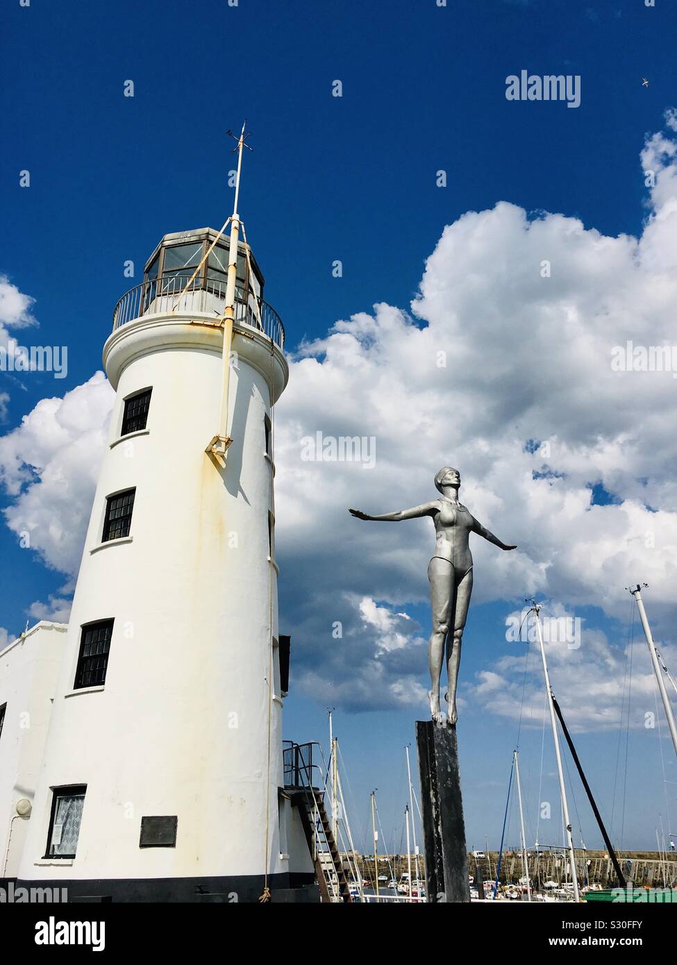 The diving belle statue on Vincent’s pier to celebrate Scarborough as being the first UK sea bathing resort with lighthouse in background, Yorkshire Stock Photo
