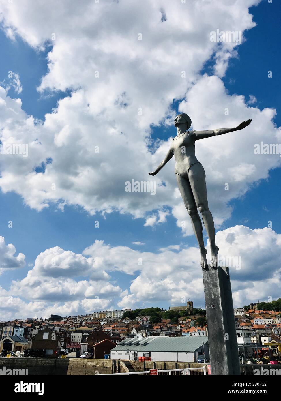 The diving belle statue on Vincent’s pier to celebrate Scarborough as being the first UK sea bathing resort with Scarborough in background, Yorkshire Stock Photo