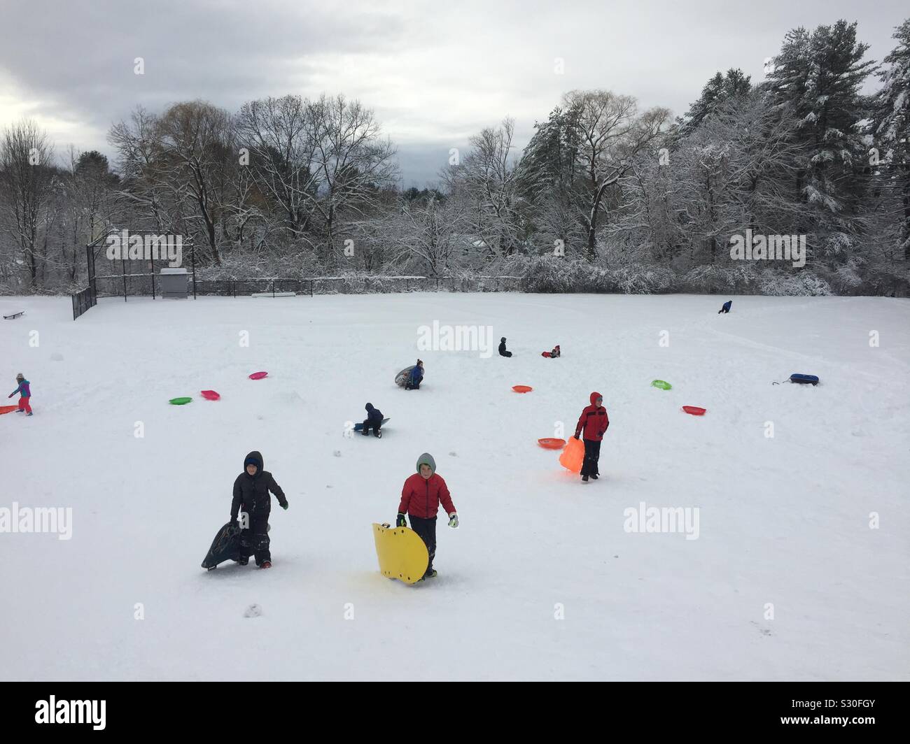 Snowy hill and sledders in Sudbury, Massachusetts on December 3, 2019. - Smartphone Captured Stock Image