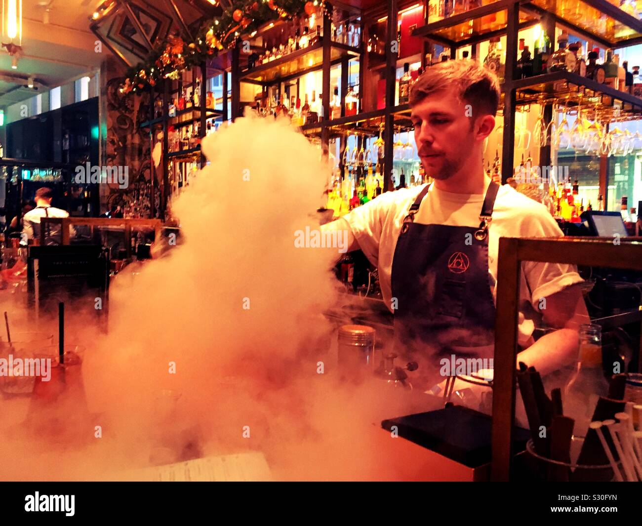 The alchemist cocktail bar. Bartender mixing a cocktail with dry ice/smoke. Liverpool nightlife - Smartphone Captured Stock Image