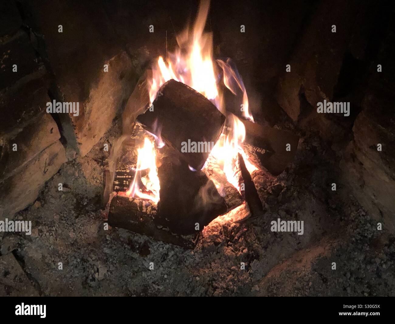 A roaring open log fire in a hearth in winter. Stock Photo