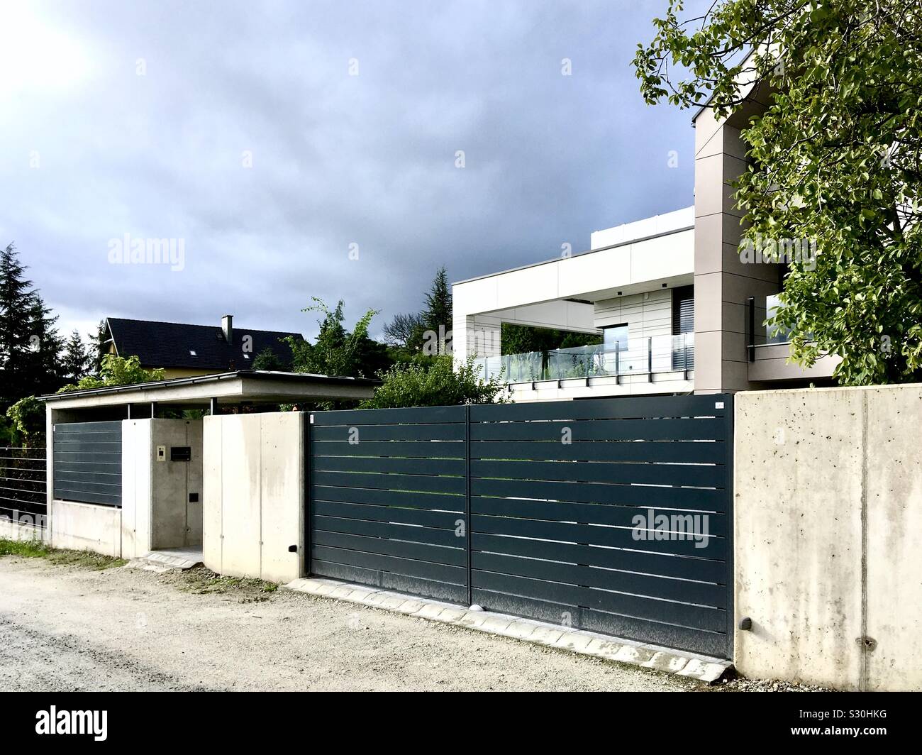 Modern white house home with concrete fence against stormy cloudy sky, Sopron, Hungary - Smartphone Captured Stock Image
