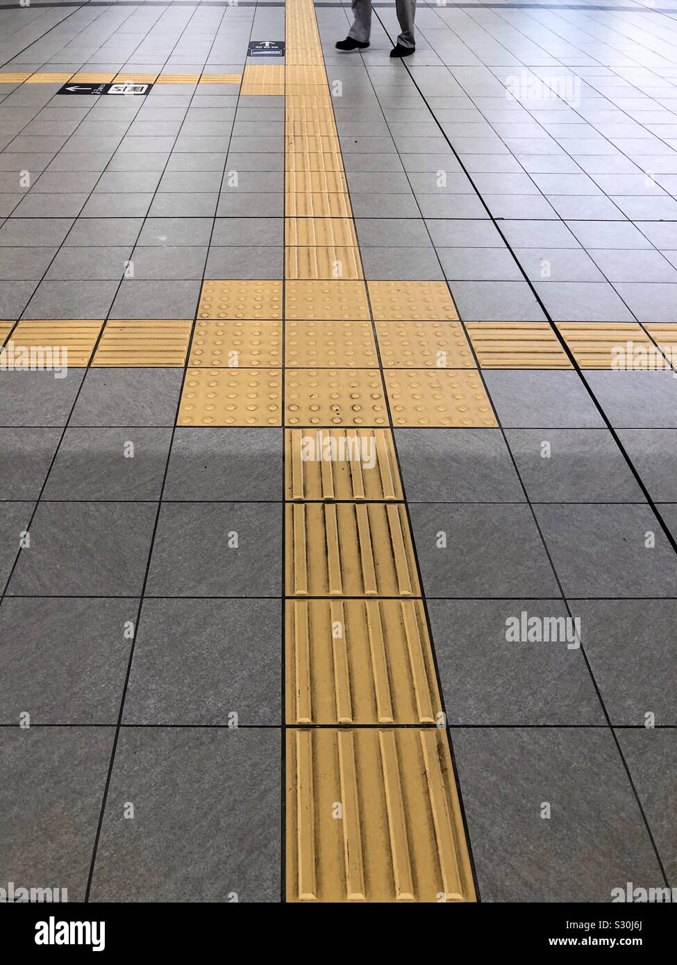 Yellow lines called Tactile Ground Surface Indicators , TGSI , or Tenji Blocks. In a Tokyo subway station in Japan. - Smartphone Captured Stock Image