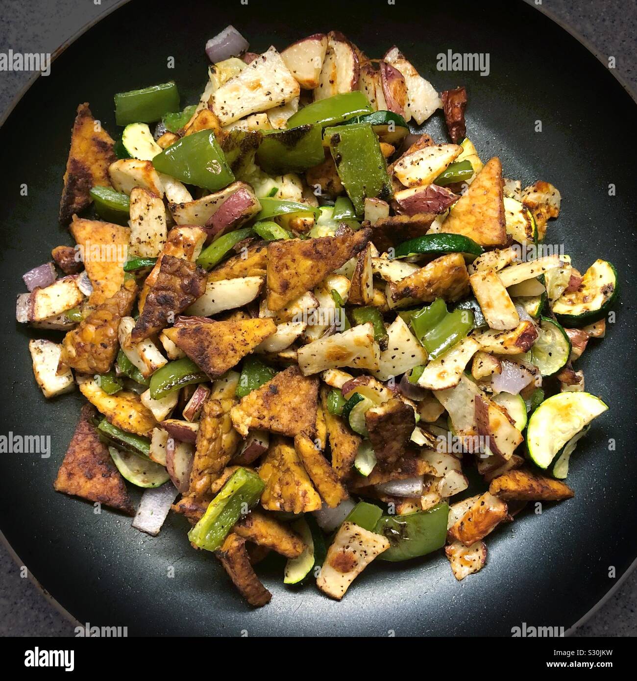 Roasted veggies and tempeh in a skillet. Stock Photo