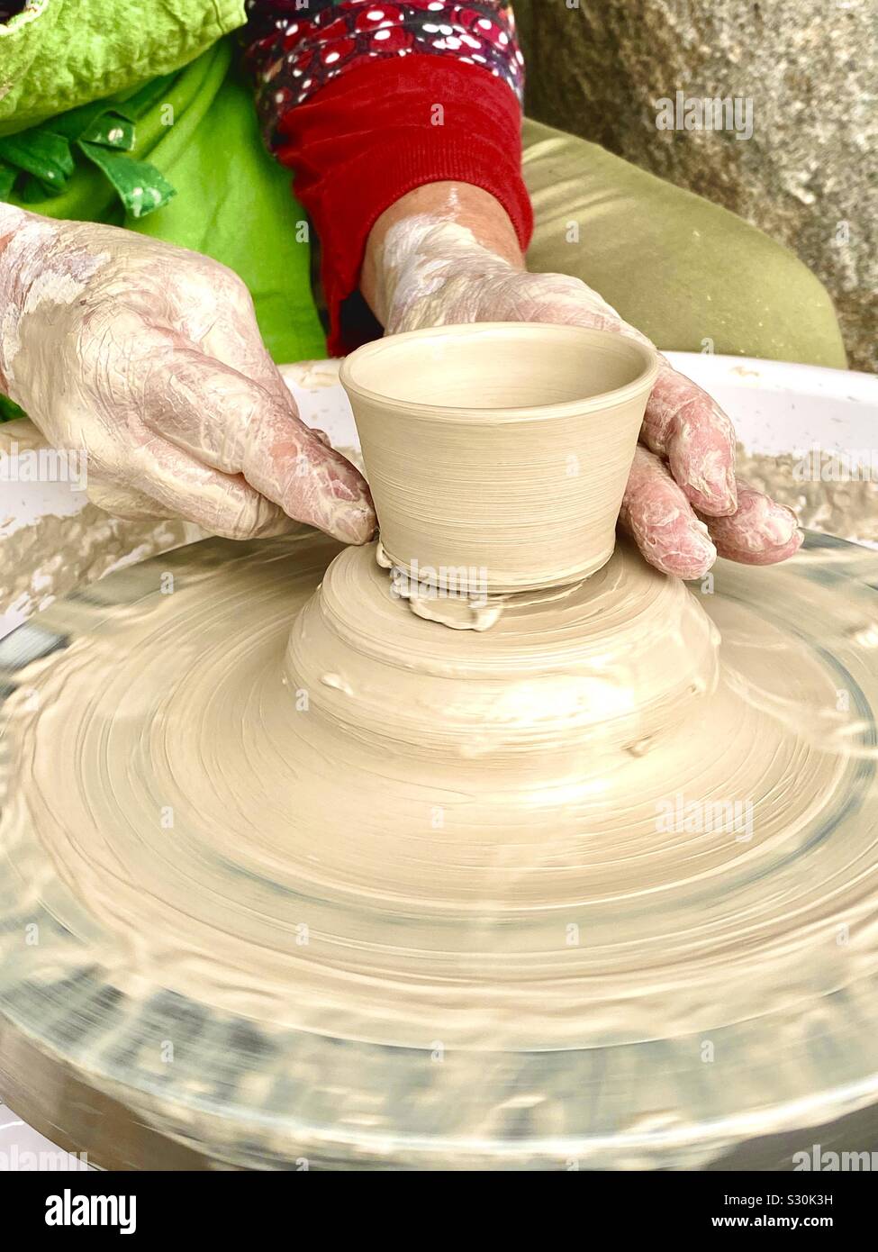 Throwing a pottery piece in green clay Stock Photo