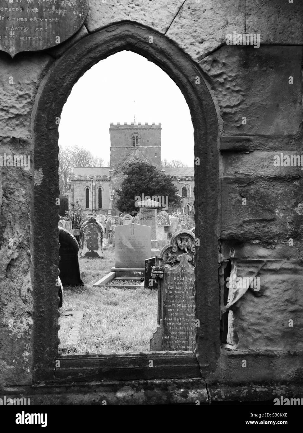 Norman style church tower viewed through the arched window of an elaborate tomb - Smartphone Captured Stock Image