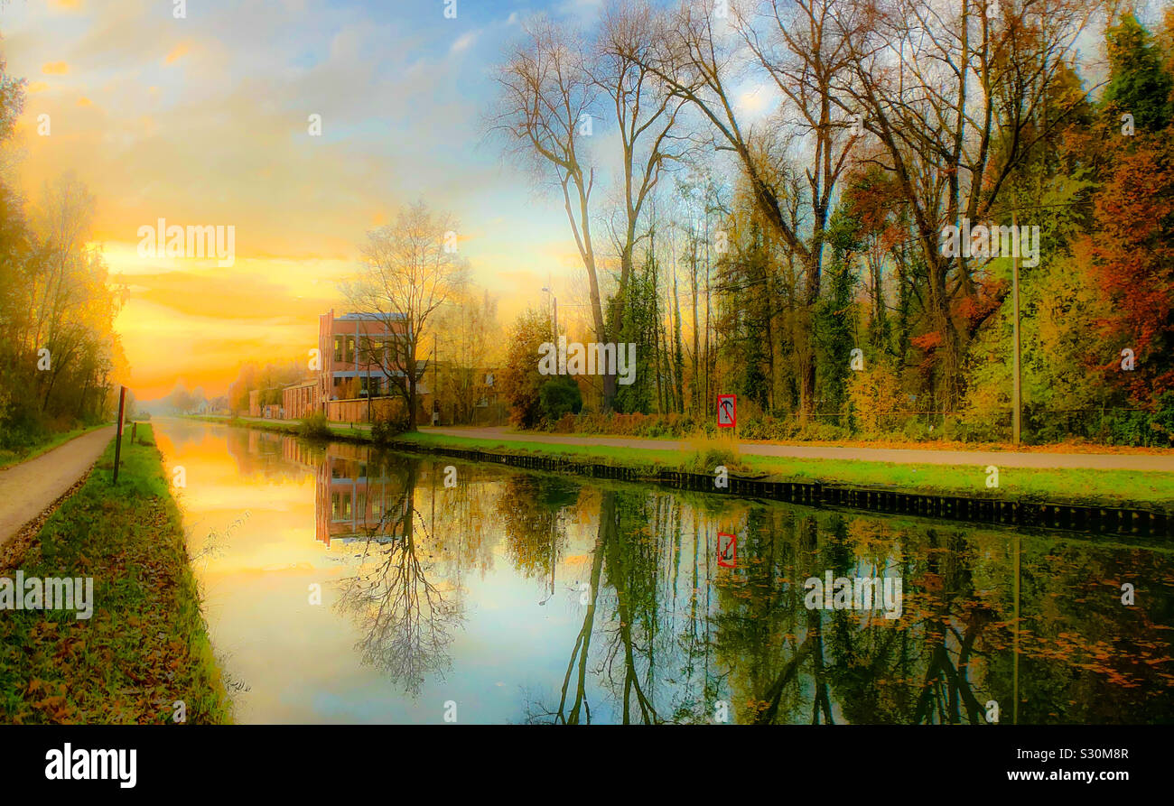 Dreamy fall landscape of a colorful sunrise or sunset sky reflected in the water of the river or canal - Smartphone Captured Stock Image