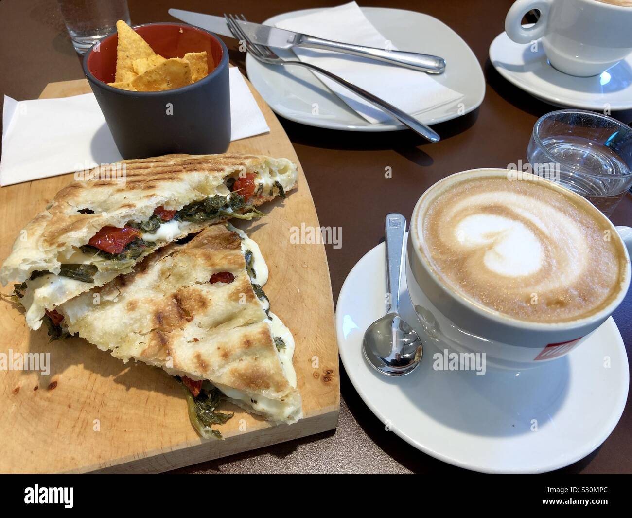 Still life of a lunch in a café in Germany of cappuccino coffee, crackers, and cheese sandwich. - Smartphone Captured Stock Image