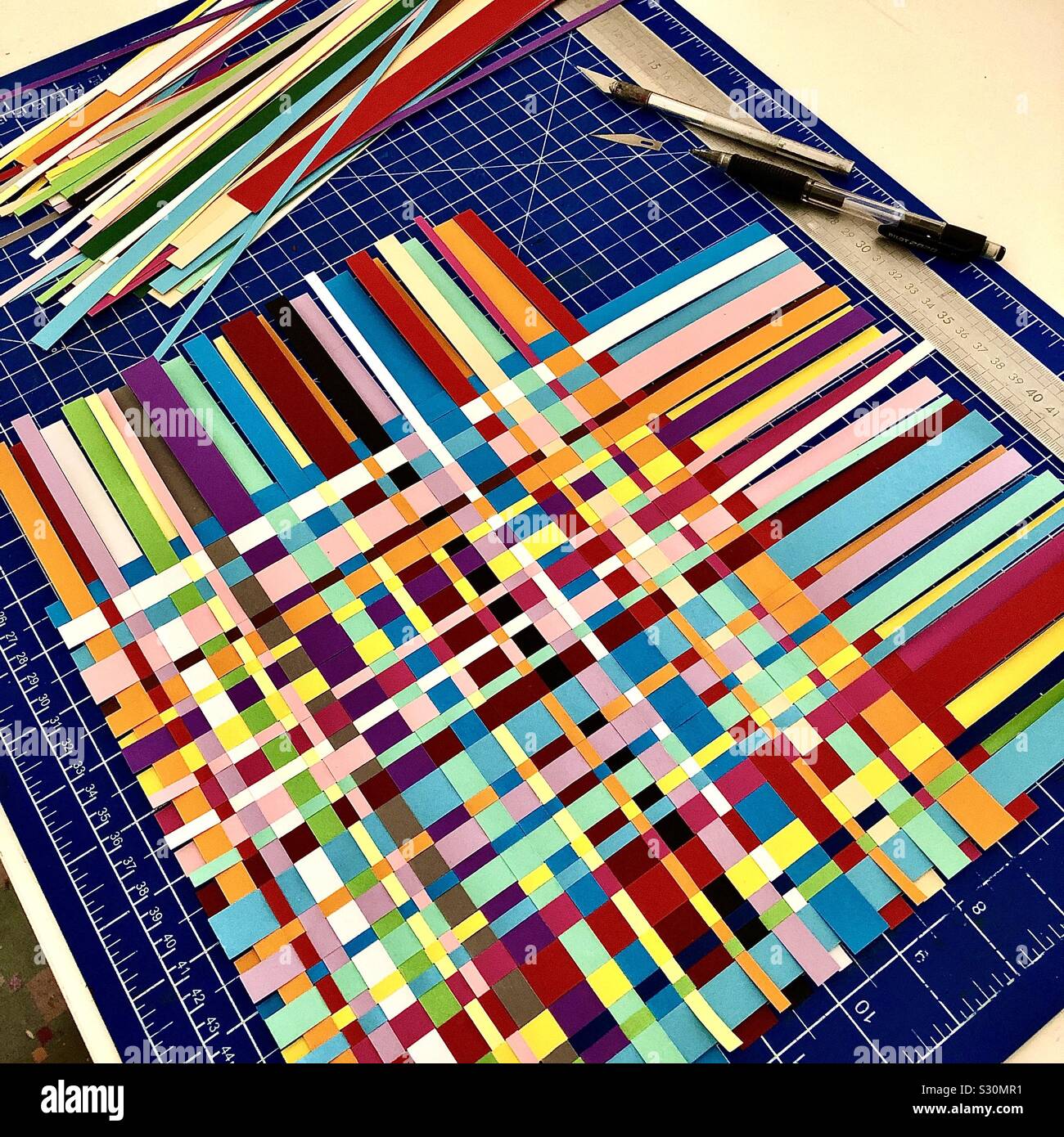 Craftwork with coloured paper strips woven together. Stock Photo