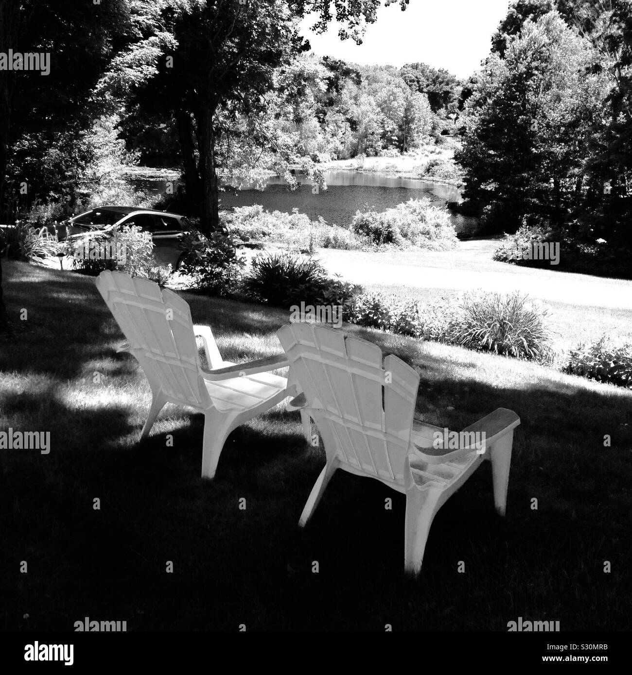 Two Adirondack chairs in New England facing the river. - Smartphone Captured Stock Image