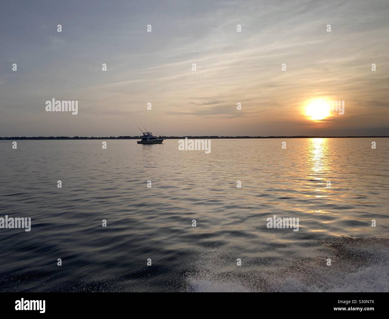 Sunset on the Gulf of Mexico with a boat going towards setting sun Stock Photo