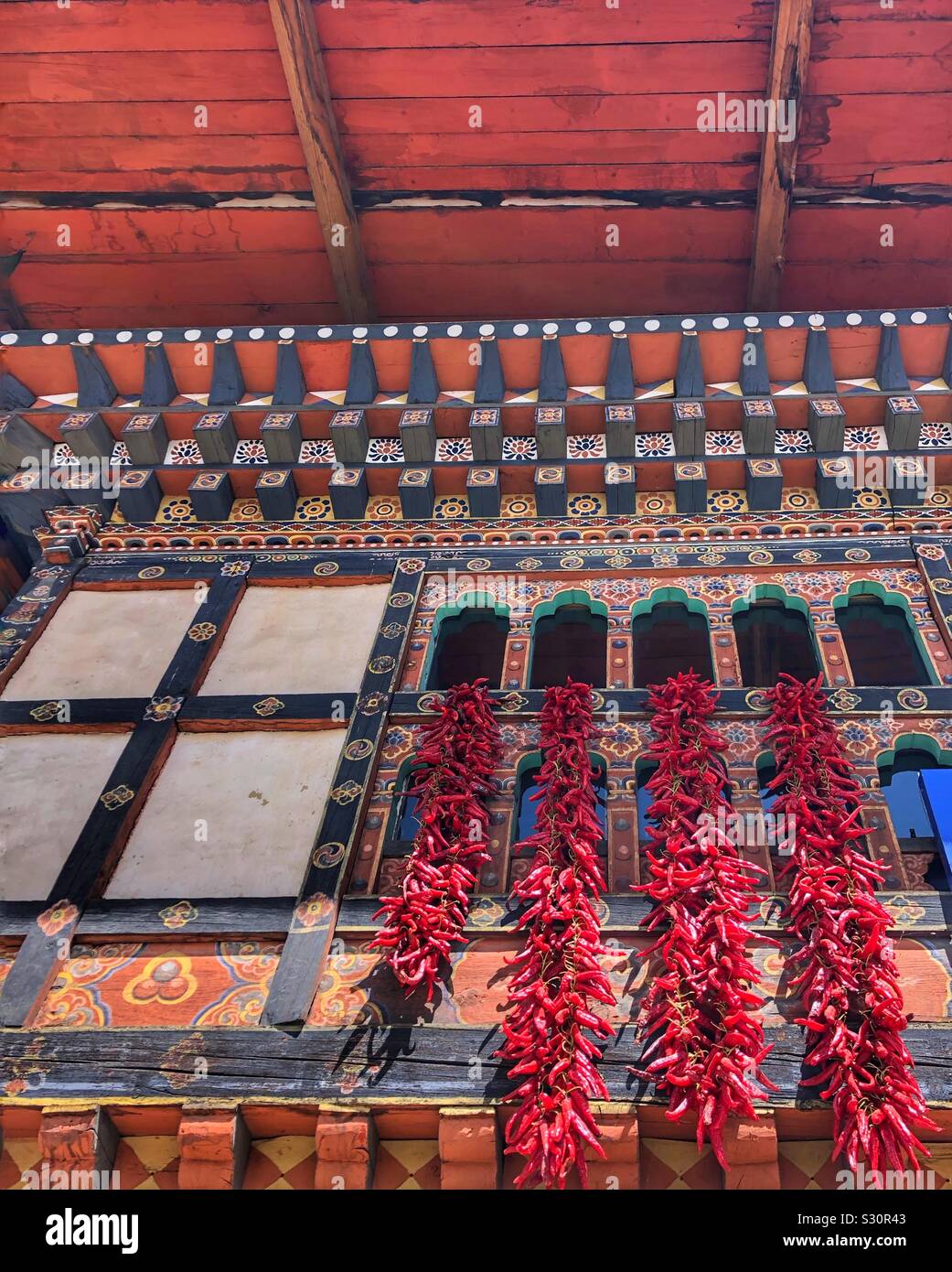 Chili peppers hanging out a window to dry in Paro, Bhutan. Stock Photo