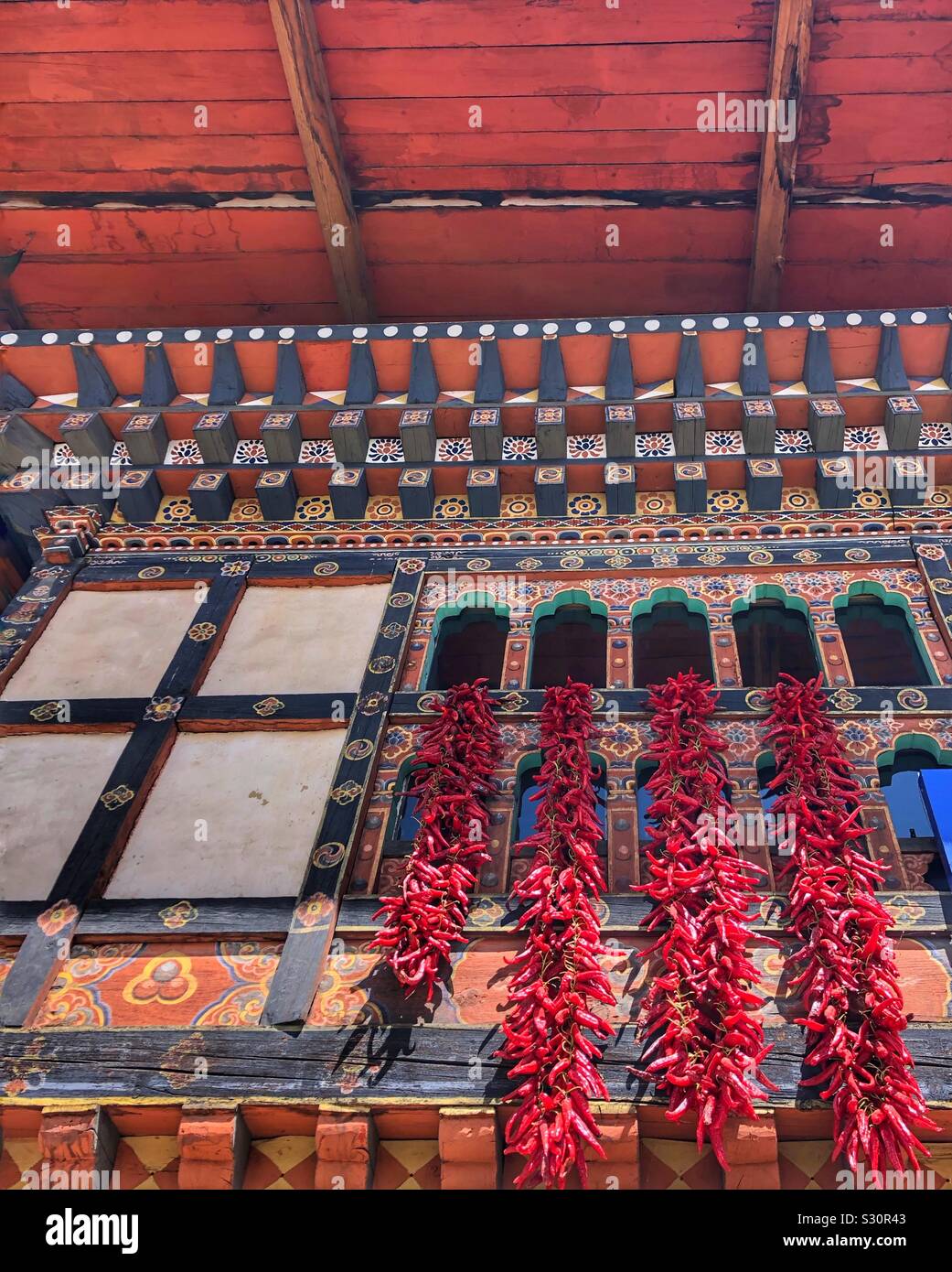 Chili peppers hanging out a window to dry in Paro, Bhutan. - Smartphone Captured Stock Image