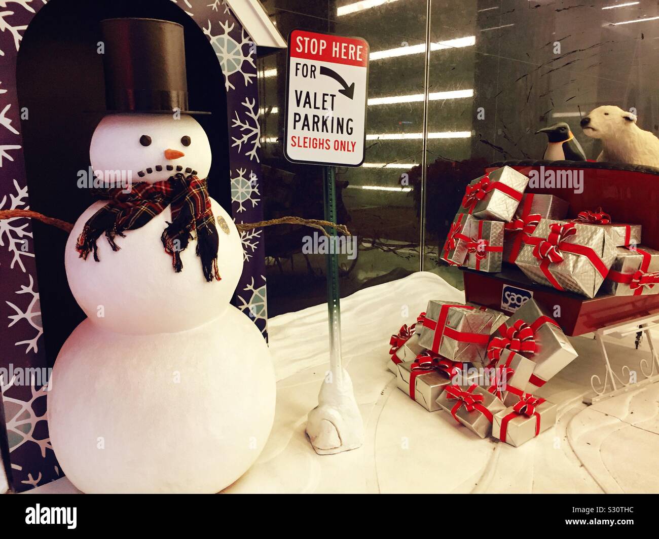 Humorous holiday display featuring a snowman and a sleigh in front of an office building on Madison Avenue, NYC, USA - Smartphone Captured Stock Image