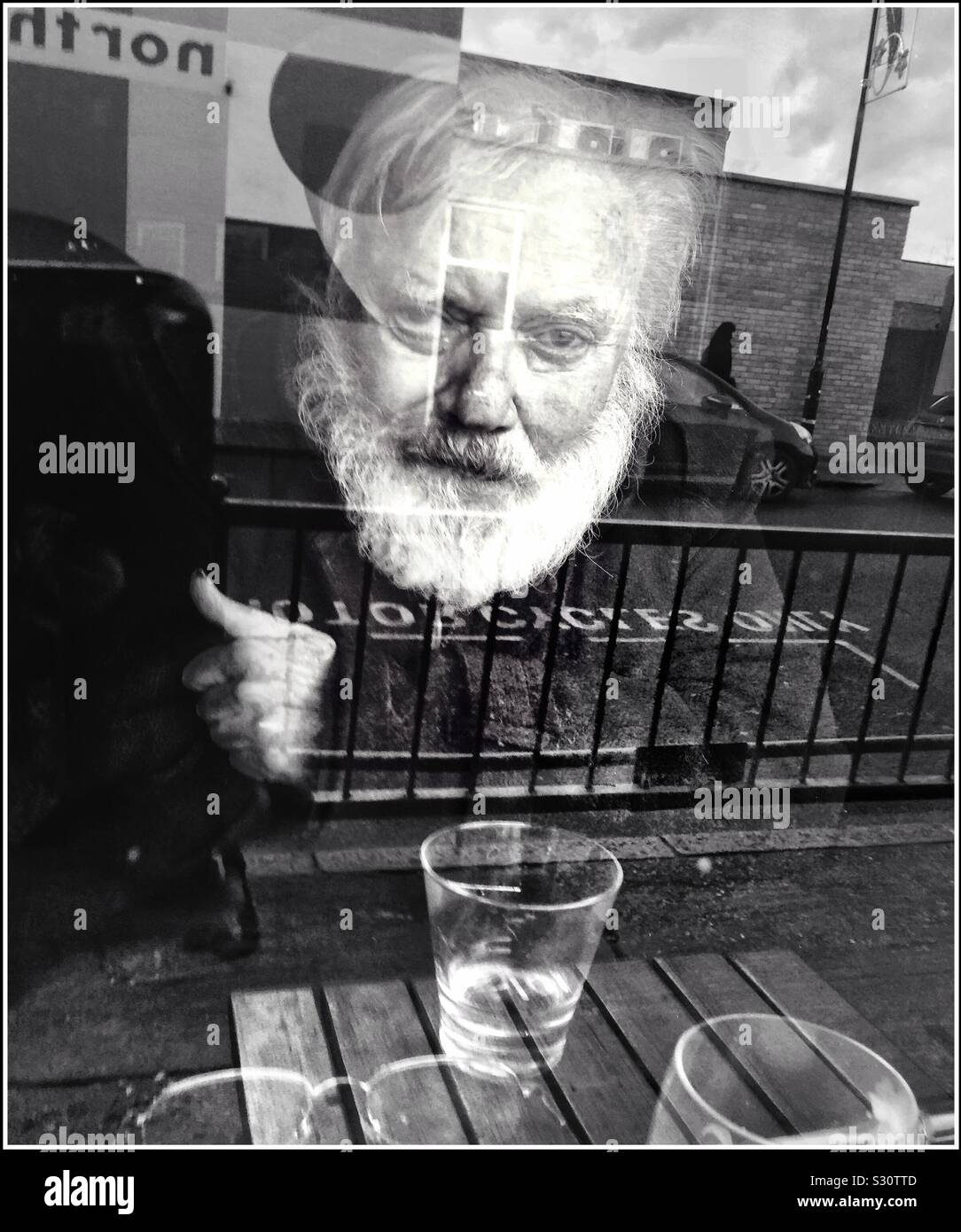 An elderly mans face seen through a pub window. Stock Photo