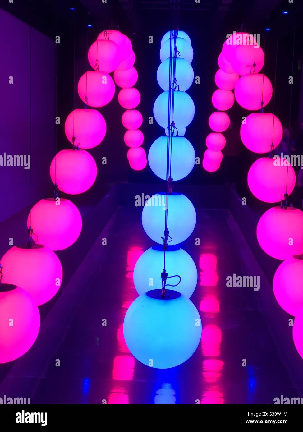 A kinetic Christmas light sculpture with lighted orbs raised and lowered to music to form patterns. Stock Photo