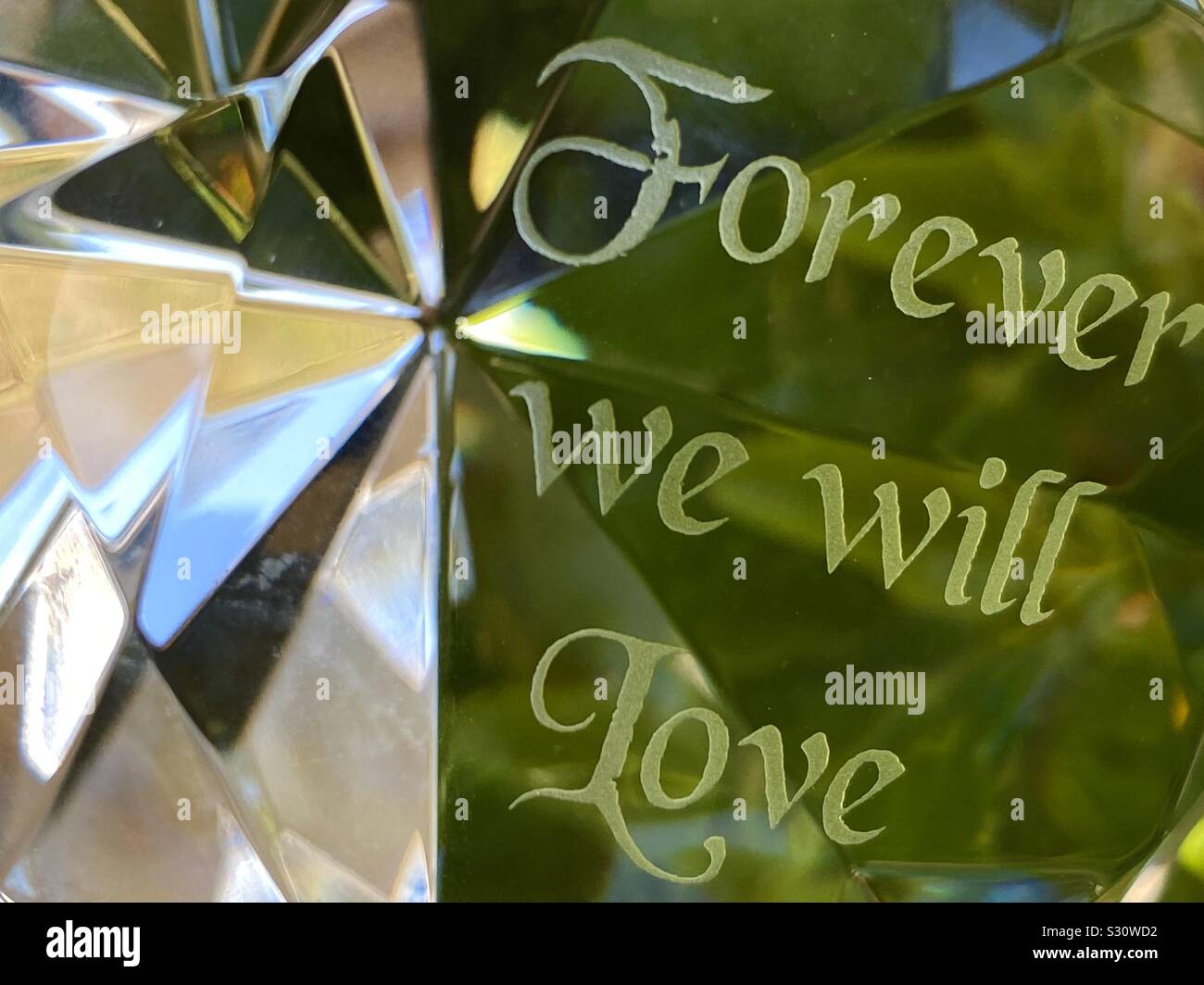 Abstract of an engraved prism with message of love using outdoor plants as background - Smartphone Captured Stock Image