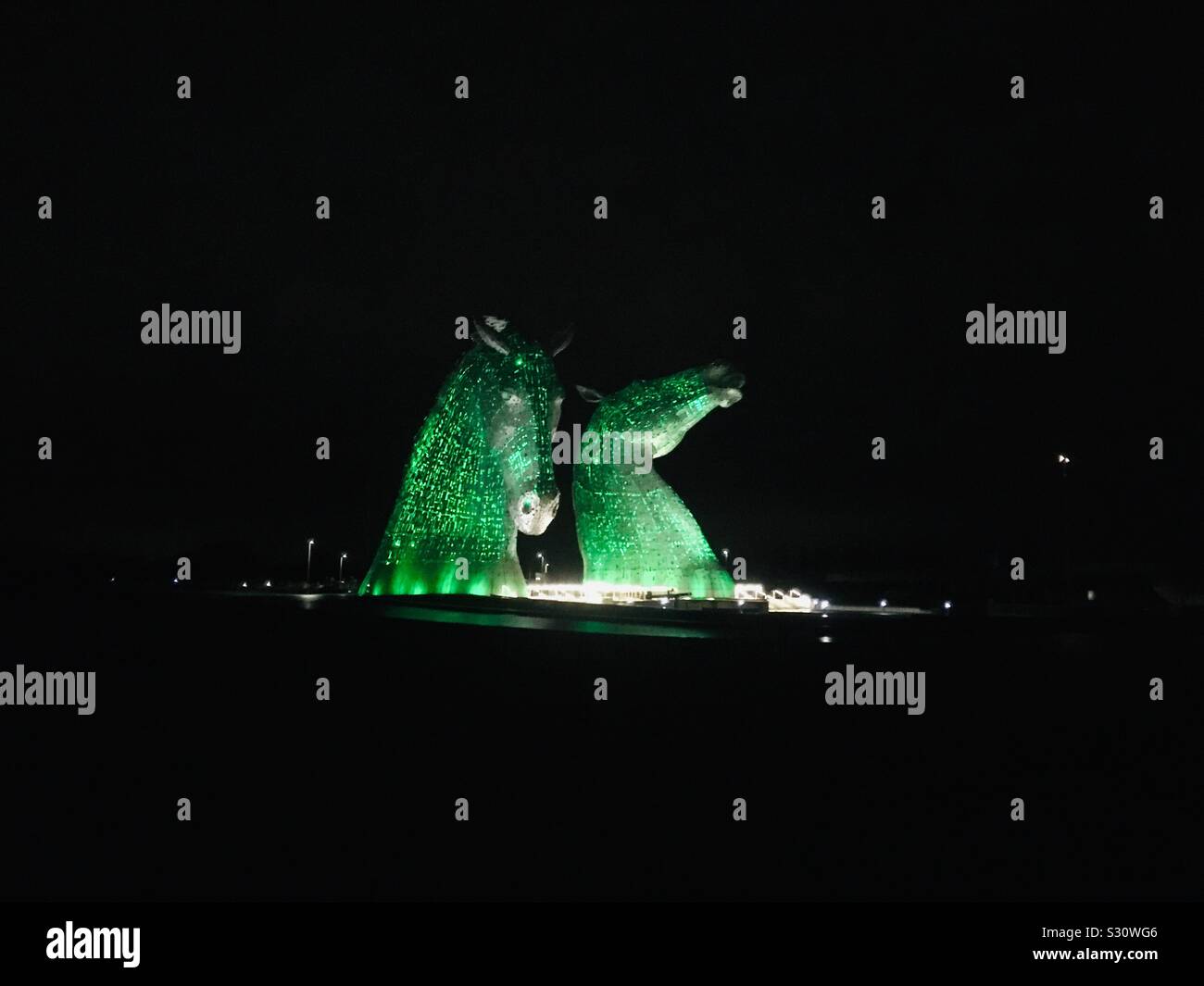 The Kelpies at night, lit up in green. Giant Horse Head Sculptures of