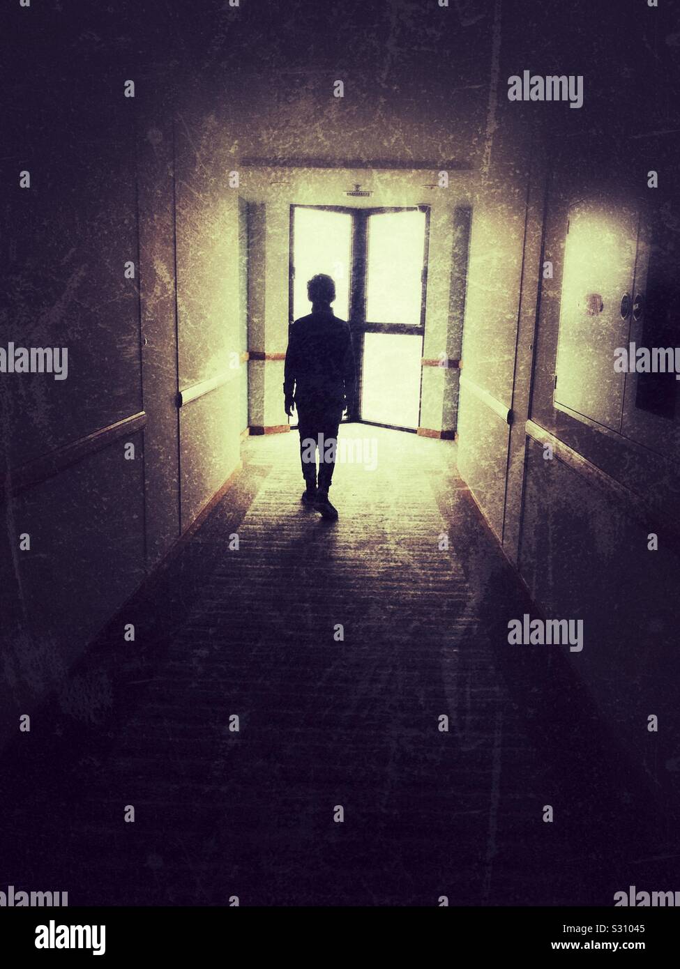 Boy walking in a narrow corridor with window at the end - Smartphone Captured Stock Image