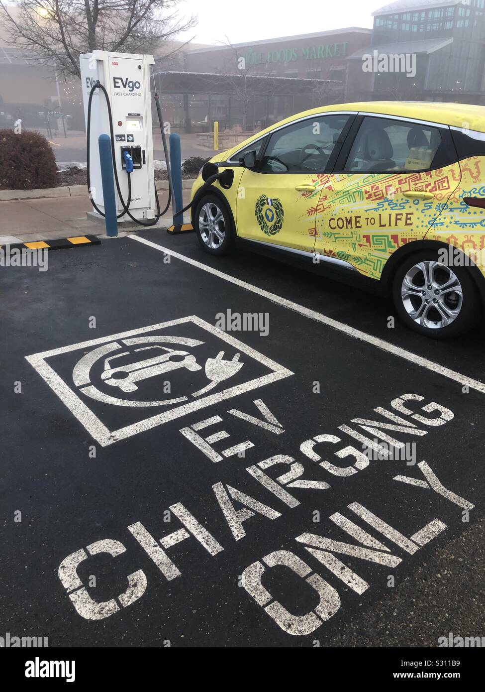 An electric Chevy Bolt charges at an EV charging station outside a