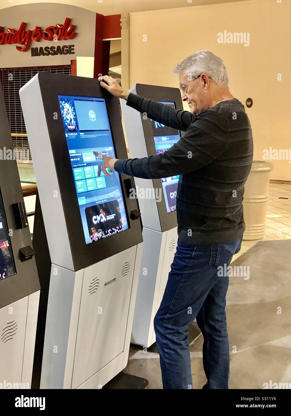 Senior man buying a movie ticket at an automated box office machine at a movie theater. - Smartphone Captured Stock Image
